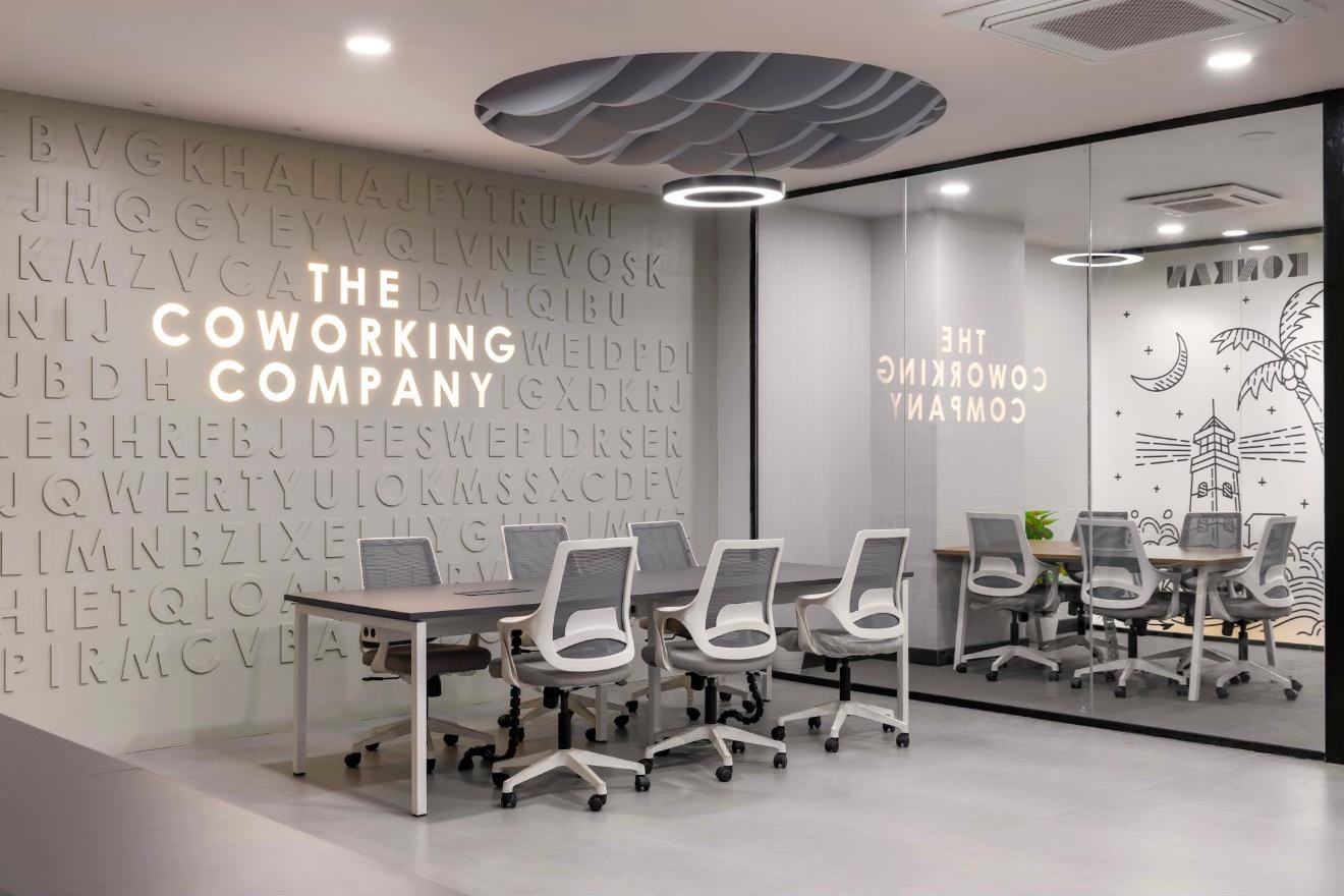 The lit Coworking Company letter wall beside a glass meeting room